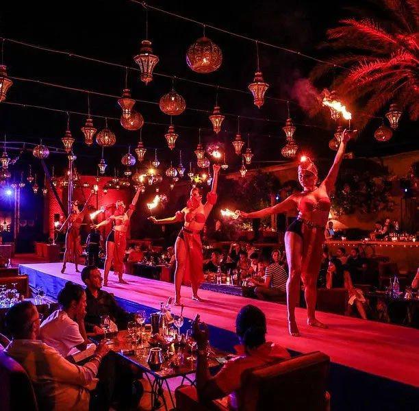 Performers on a lantern-lit stage at a Marrakech dinner-show restaurant, diners watching from their tables