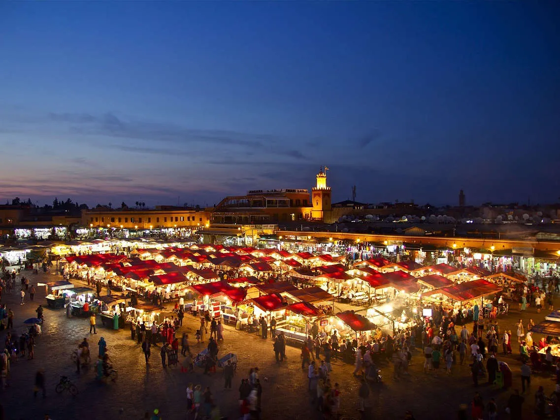 A quiet lantern-lit alley in the Marrakech medina at night, warm light spilling from a doorway